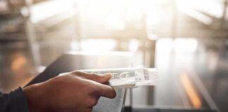 Hand holding a passport and boarding pass at an airport counter
