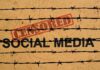 Barbed wire over the words social media and censored stamp