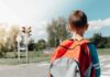 child with backpack waiting at crosswalk
