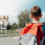 child with backpack waiting at crosswalk
