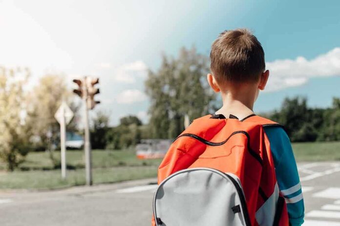 child with backpack waiting at crosswalk