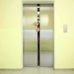 Elevator doors closing with hands reaching through the gap