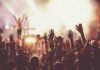 Stadium Ultimatum Knocks Macklemore Off Tour Crowd at concert with raised hands near bright stage lights