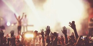 Crowd at concert with raised hands near bright stage lights