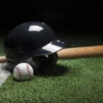 Baseball helmet, bat, and ball on artificial turf