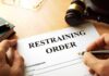 Restraining order form on a desk with hands holding a pen