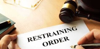 Restraining order form on a desk with hands holding a pen