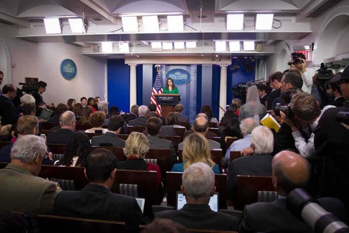 shutterstock_744405130-4 Press secretary at podium addressing reporters in briefing room
