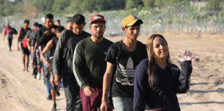Line of people walking along a dirt path outdoors