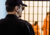 Security guard watching inmates behind jail bars