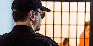 Security guard watching inmates behind jail bars