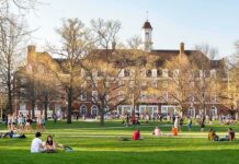 Off-Campus Remark, Instant Consequence Students relaxing on a campus quad in front of a brick academic building