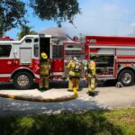 Firestorm Halted, Cat Comes Home Fire truck with firefighters operating hoses on a residential street