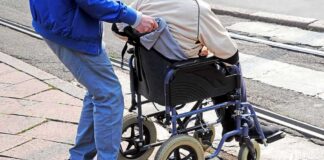 Caregiver pushing person in wheelchair over curb