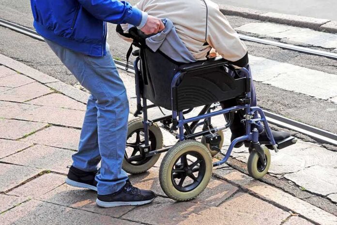 shutterstock_1198667221-1 Caregiver pushing person in wheelchair over curb