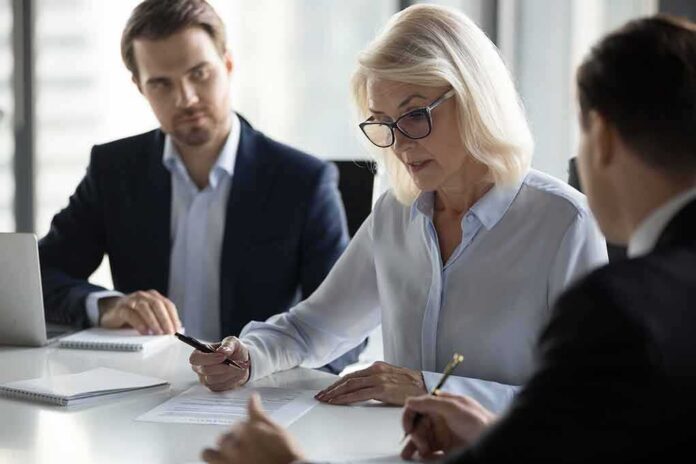 shutterstock_1249021717 Businesswoman signing a document at a meeting table