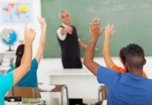 Classroom Kick Sparks Felony Arrest Students raising hands in a classroom while teacher points