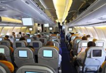 A Cockpit Attack Tests Aviation Security Interior view of an airplane with passengers seated and using in-flight entertainment screens
