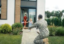 soldier kneeling to embrace daughter on home walkway