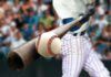 Baseball player hitting a ball with a wooden bat