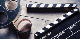 Film reel and clapperboard on wooden surface
