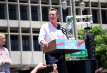 Gavin Newsom speaking at an outdoor rally podium