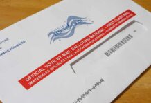 Mail-in ballot envelope with red label on wooden table