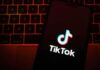 TikTok app logo on a smartphone over a laptop keyboard