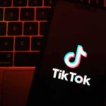 TikTok app logo on a smartphone over a laptop keyboard