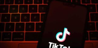 TikTok app logo on a smartphone over a laptop keyboard