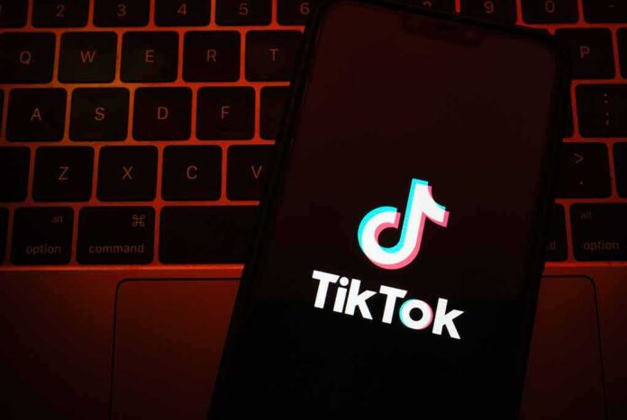 shutterstock_1794882403 TikTok app logo on a smartphone over a laptop keyboard