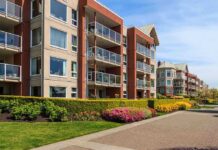 Campus Fall Horror – One Tiny Device Missing Modern apartment buildings with balconies and landscaped gardens on a sunny day