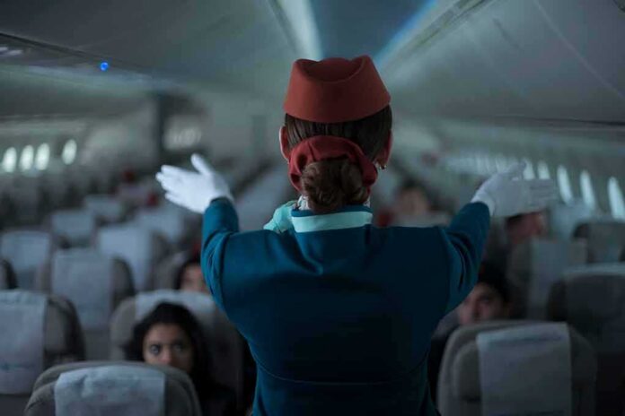 shutterstock_2068194518 Flight attendant giving safety demonstration in airplane aisle