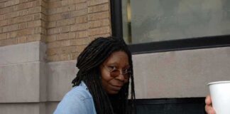 Whoopi Goldberg outdoors in a denim jacket looking at the camera