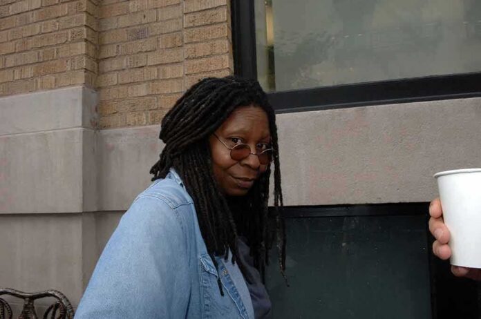 shutterstock_2117633720 Whoopi Goldberg outdoors in a denim jacket looking at the camera