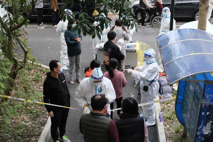 Christian Jones and others wait at an outdoor COVID-19 testing site with staff in protective suits