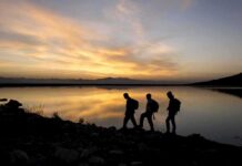 28-Year Walk Ends With Freezing Channel Gamble hikers silhouetted by a lake at sunset