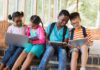 Children using laptops and tablets on school steps
