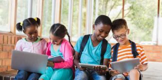 Children using laptops and tablets on school steps