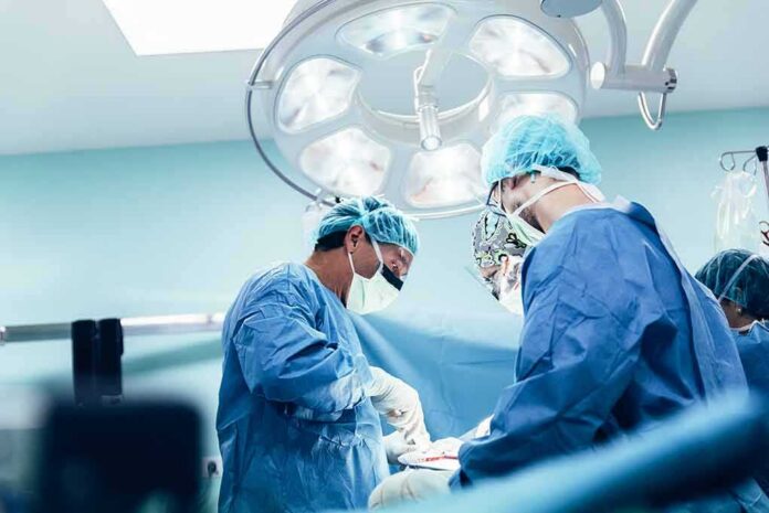 shutterstock_636996778 surgeons performing an operation under bright surgical lights