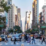 Busy city street with pedestrians crossing and yellow taxis