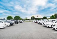 Rape Charge Erupts – 2:48 P.M., Lot 6 Parking lot lined with cars under a blue sky